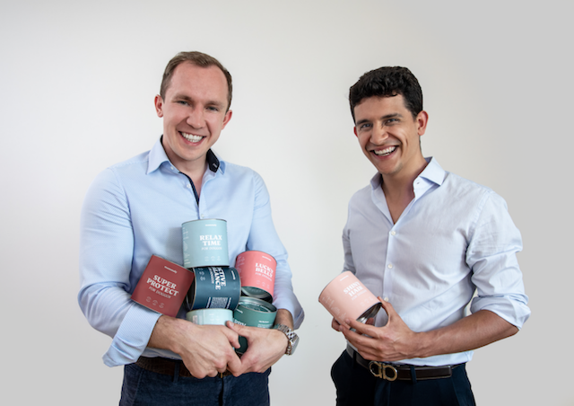 two white men standing smiling and holding mammal treat tubs