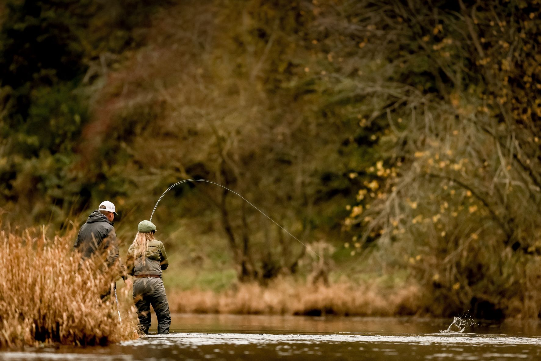 fishermen standing by river casting into water