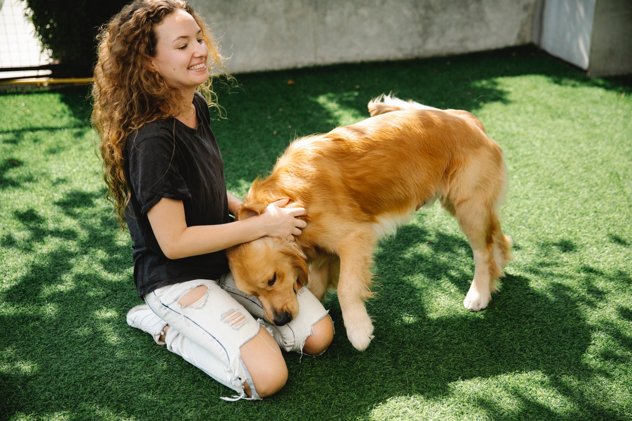 happy woman petting dog on lawn