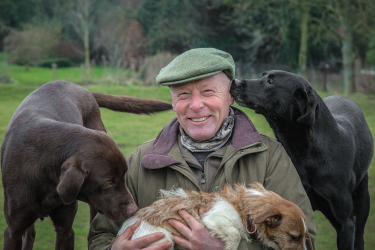 Jonathan Roberts surrounded by labradors with Jack Russell terrier in his arms